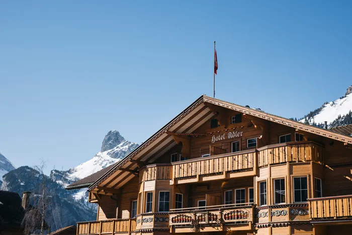 Chalet-Hotel Adler, Fassade mit Balkonen und Blick auf die Berge