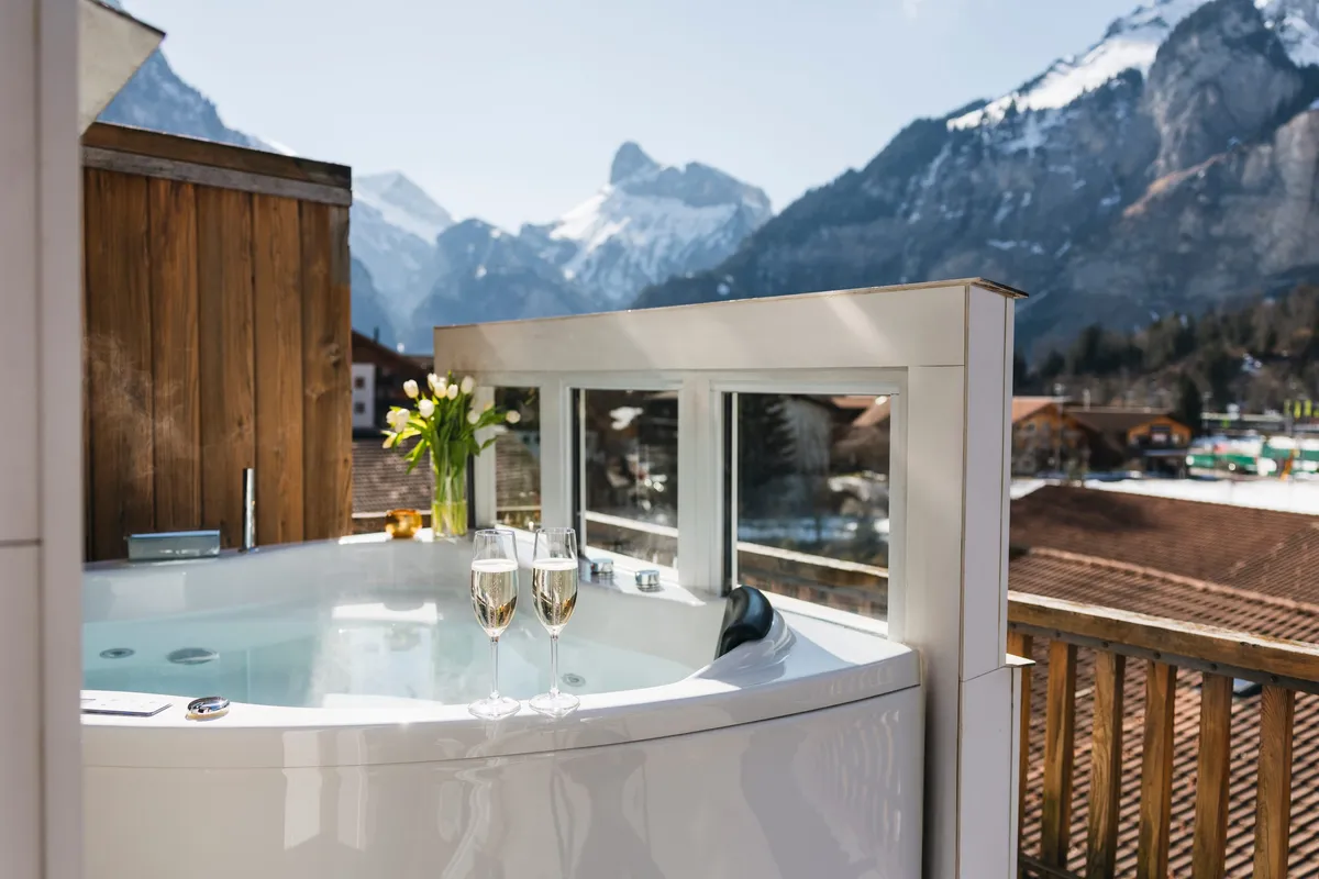 Whirlpool mit Champagnergläsern und Blick auf die Berge von Kandersteg
